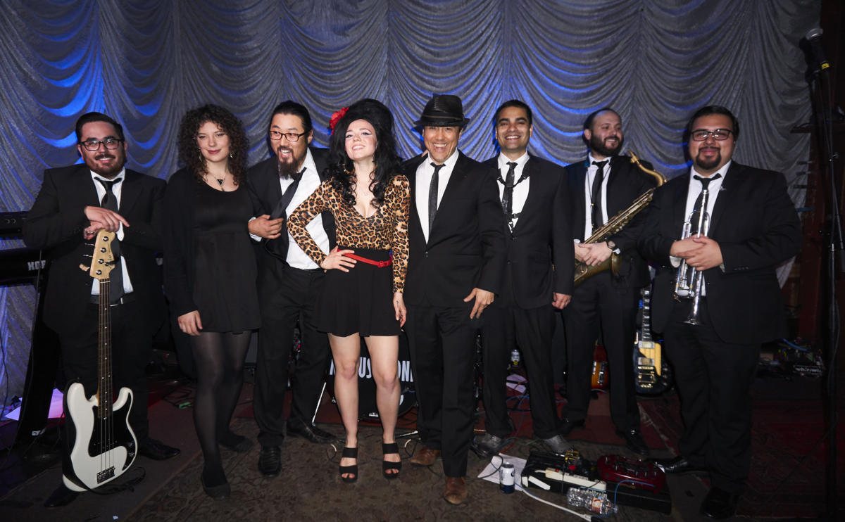 The members of Missus Jones standing together in suits, the singer at center
